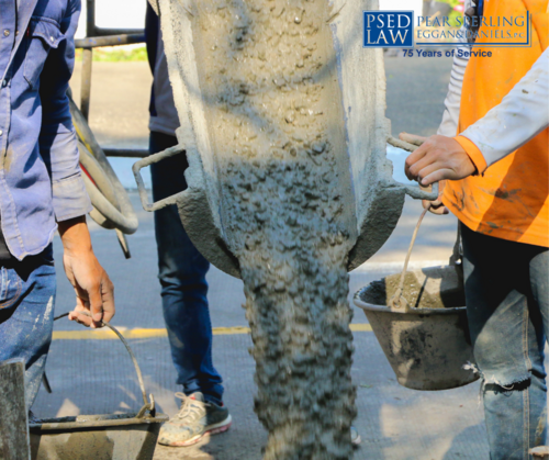 two construction workers pouring cement